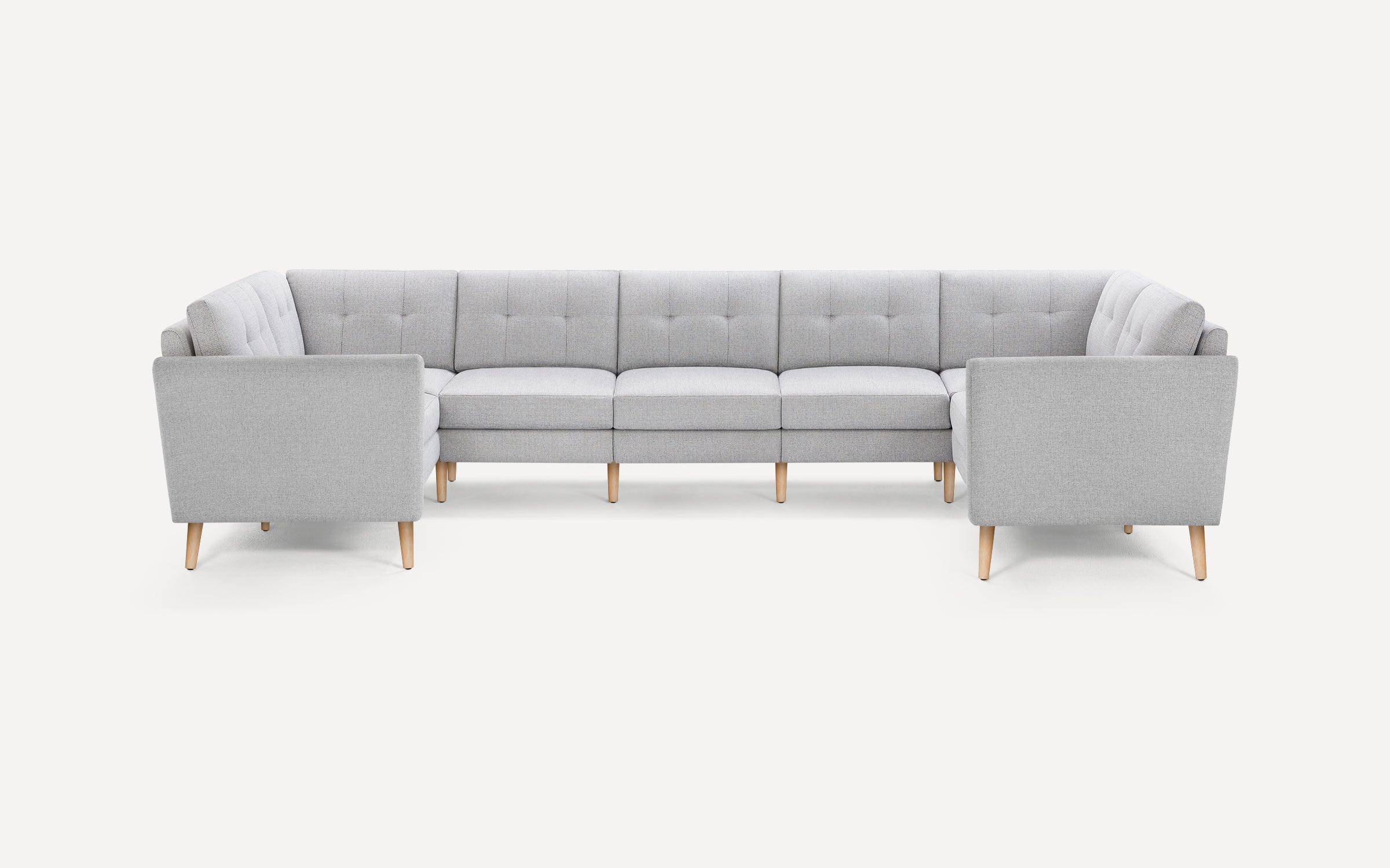 Light gray fabric U-shaped sectional sofa with tufted back cushions and wooden tapered legs on a white background.
