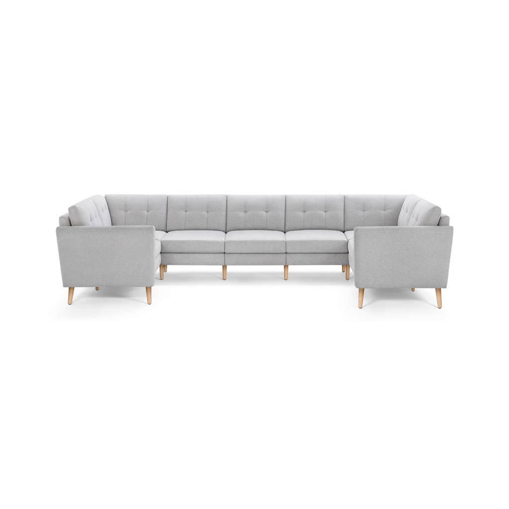 Light gray upholstered U-shaped sectional sofa with tufted back cushions and light wood tapered legs.