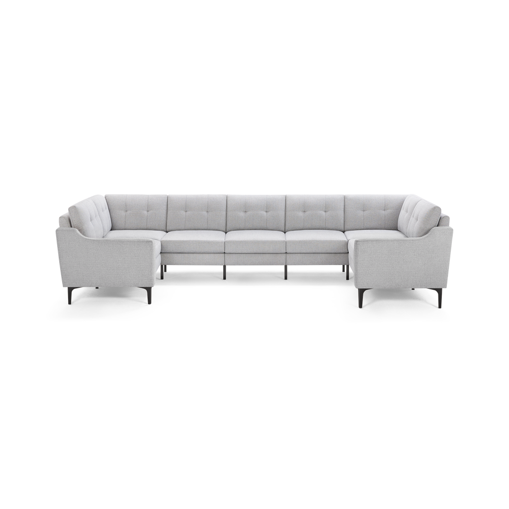Light gray upholstered large U-shaped sectional sofa with tufted backs and slender black legs on a white background.