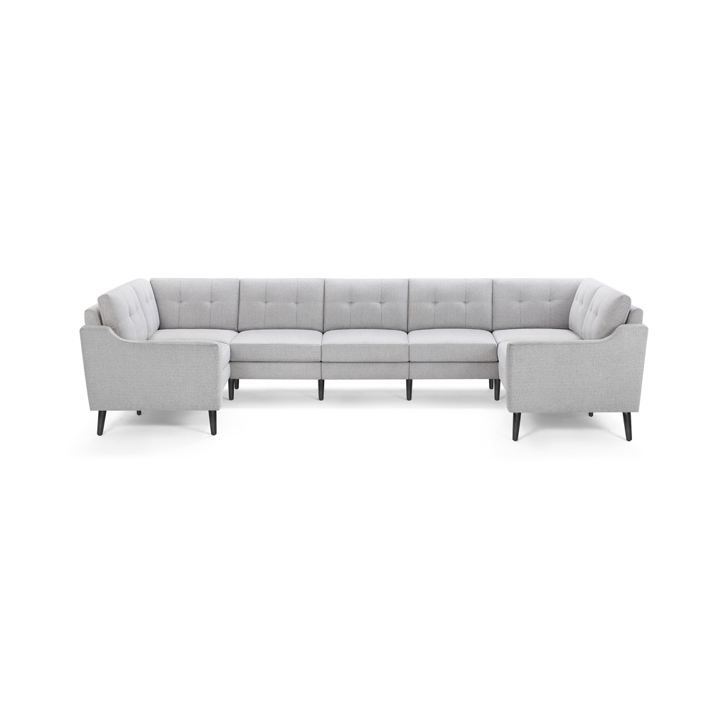 Light gray upholstered U-shaped sectional sofa with tufted back cushions and angled black legs, providing modern and spacious seating.