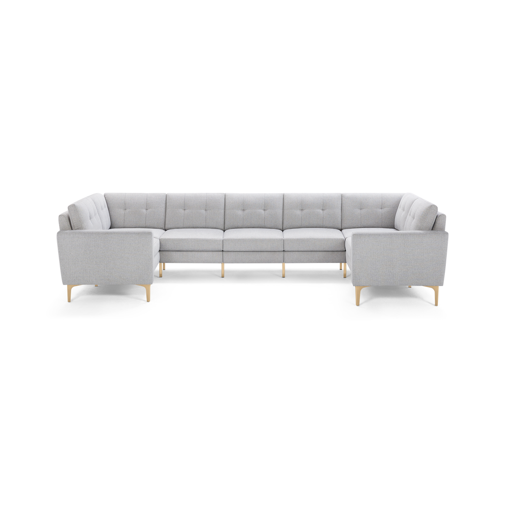 Large light gray upholstered sectional sofa with tufted cushions and light wooden legs, arranged in a spacious U-shape.