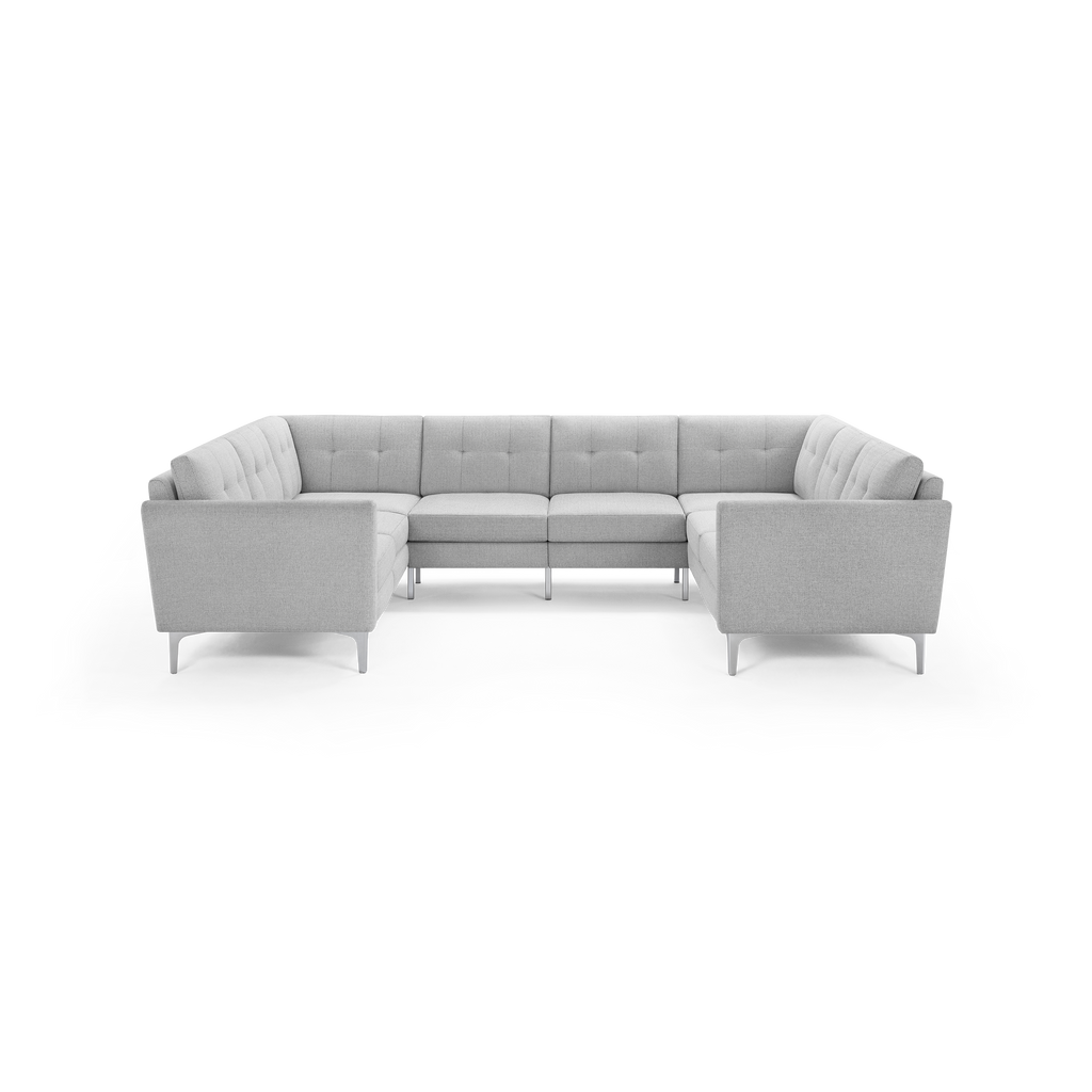 Light gray fabric U-shaped sectional sofa with tufted back cushions and modern metal legs, set against a black background.