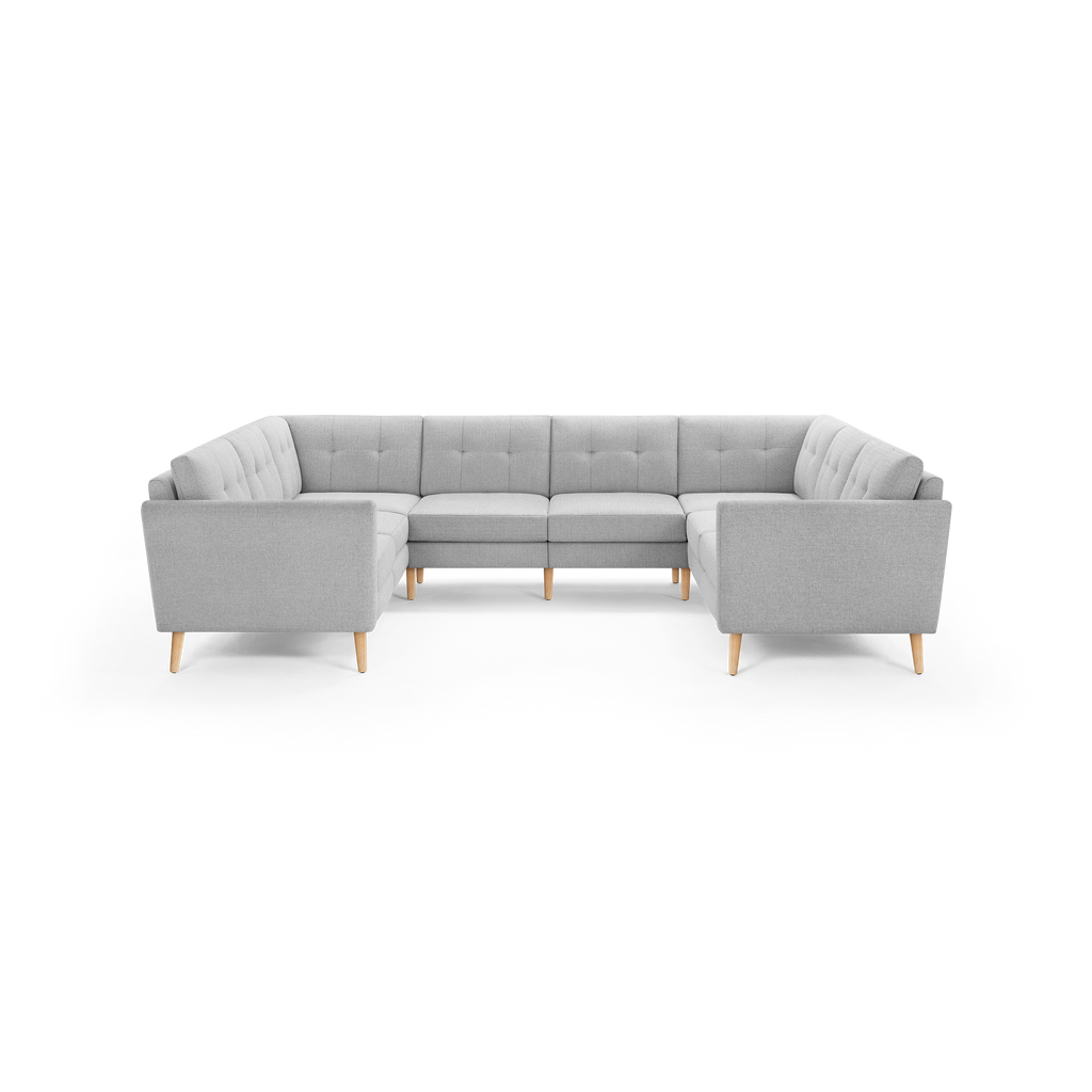 Light gray U-shaped sectional sofa with tufted back cushions and light wooden legs, designed for spacious seating.