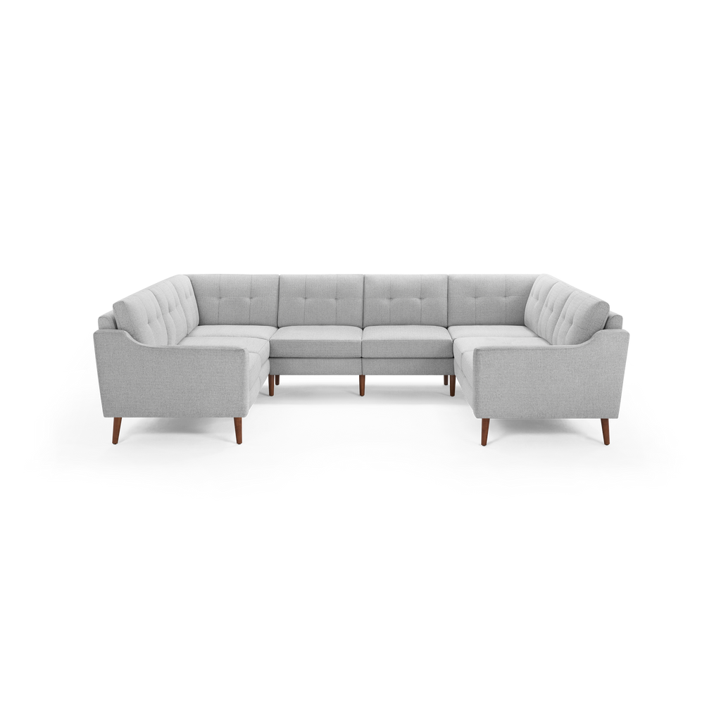 Light gray upholstered U-shaped sectional sofa with tufted back cushions and wooden tapered legs, modern mid-century design.