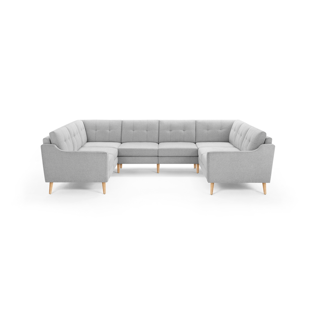 Light gray upholstered U-shaped sectional sofa with tufted back cushions and wooden tapered legs, designed for spacious seating.