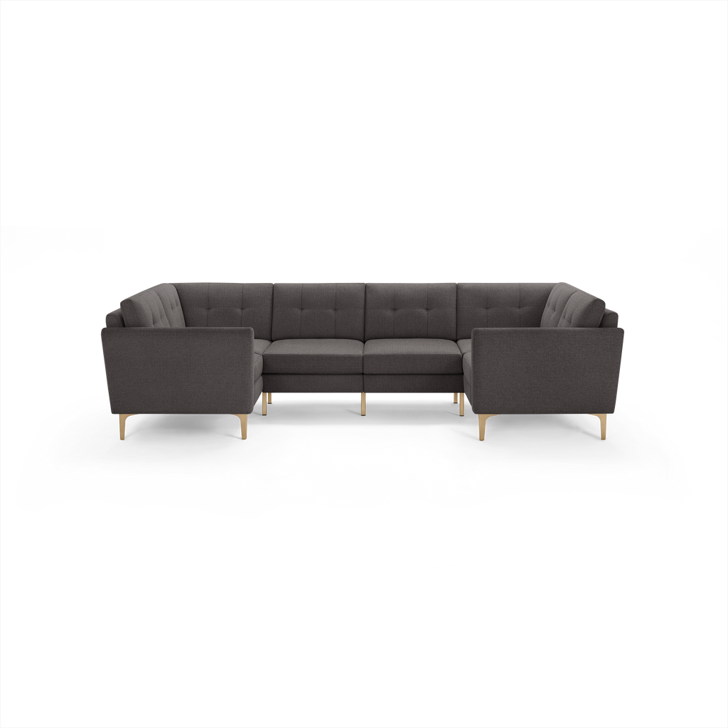 Dark gray fabric U-shaped sectional sofa with tufted cushions and light wooden legs on a black background.