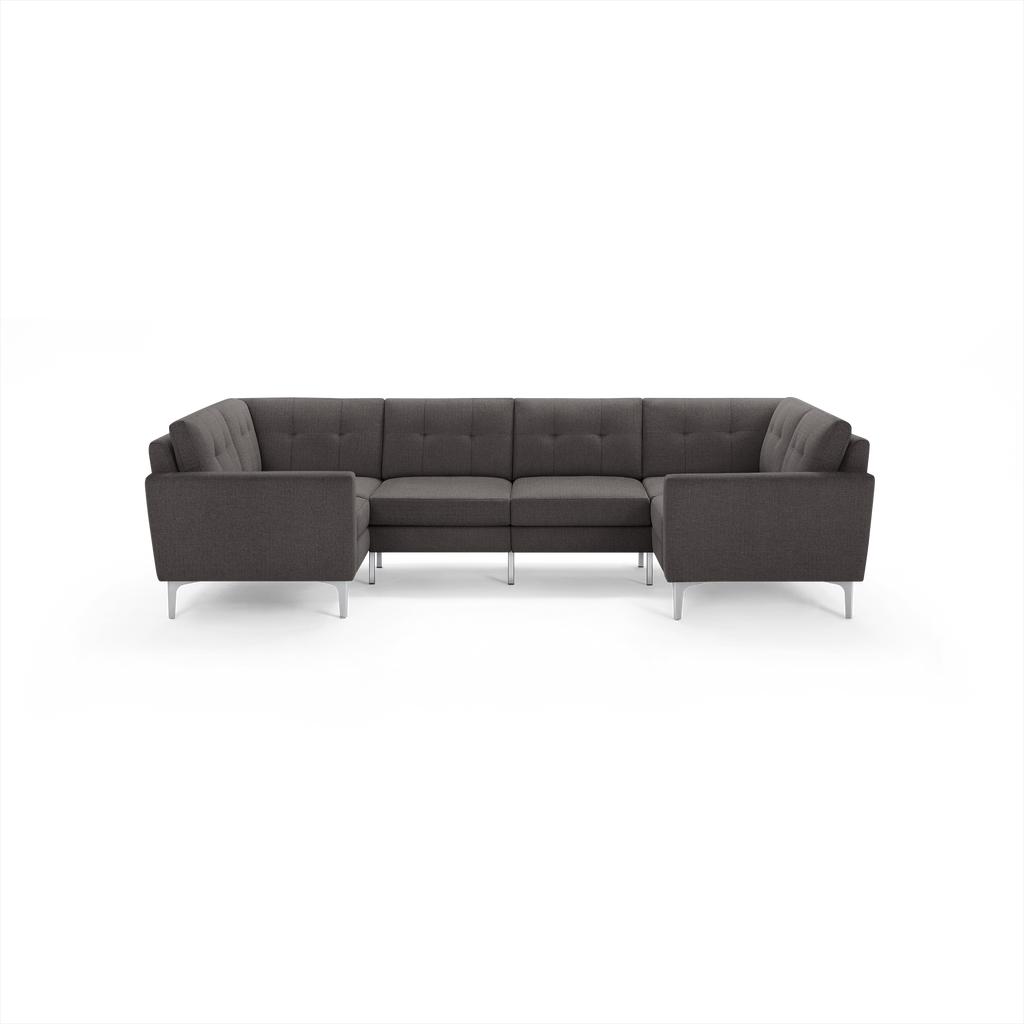 Dark gray modern U-shaped sectional sofa with tufted back cushions and slim metal legs on a black background.