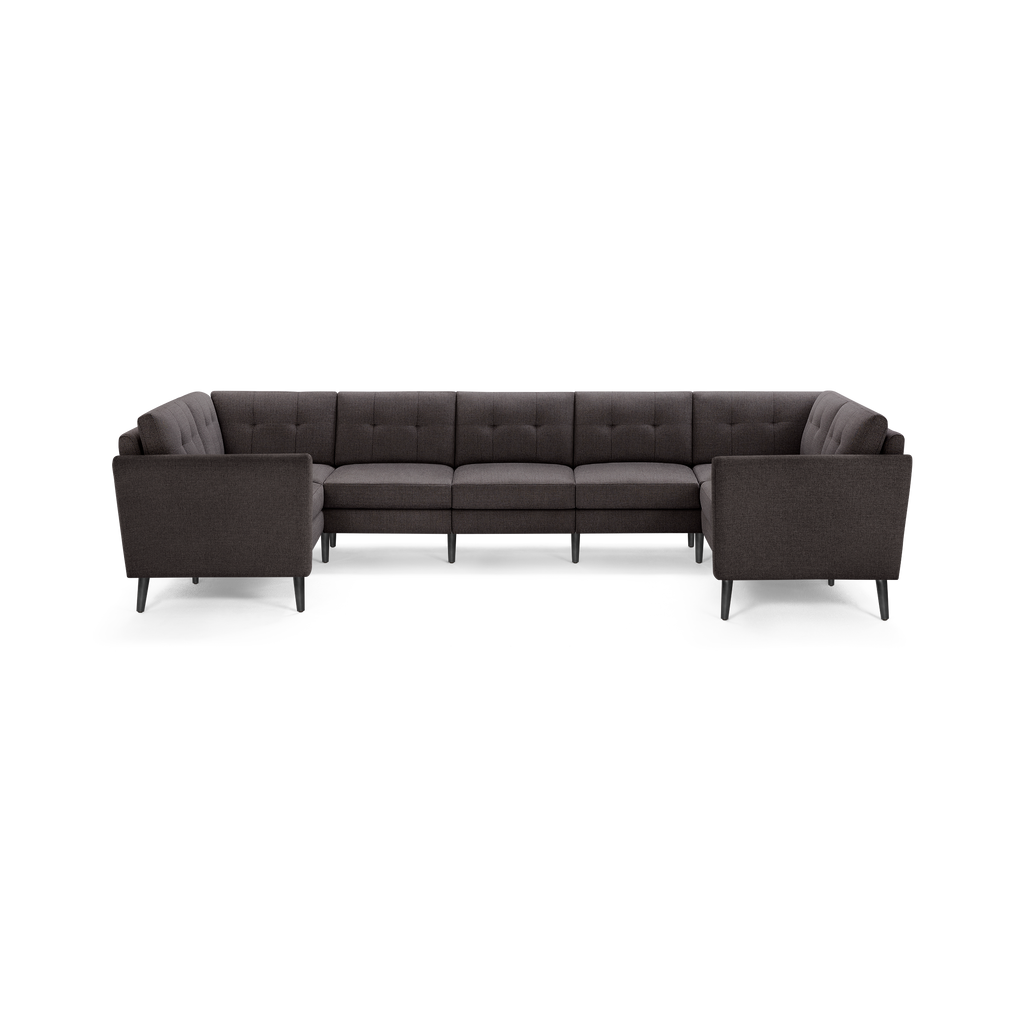 Large dark gray L-shaped sectional sofa with tufted back cushions and slim black legs, designed for modern living rooms.