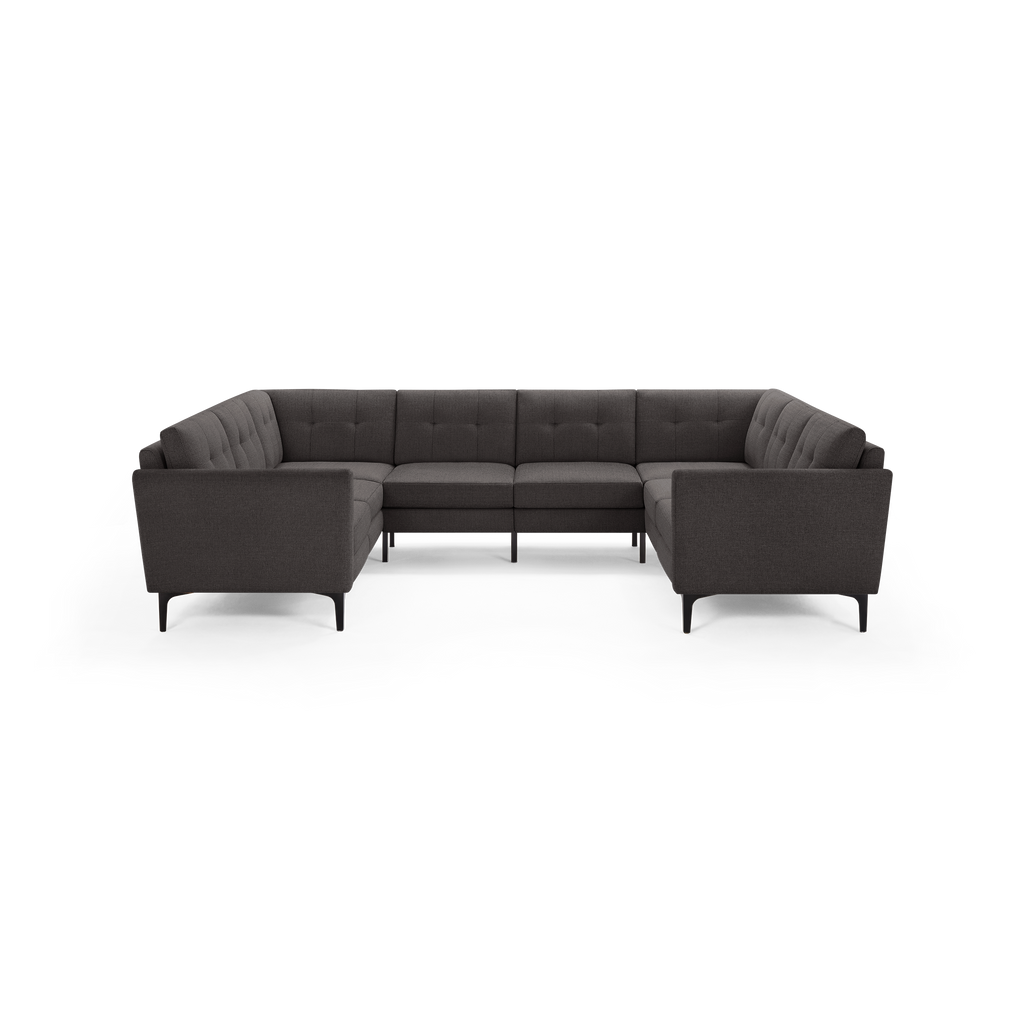 Dark gray fabric sectional sofa with tufted back cushions and slim black metal legs, arranged in a U-shape.