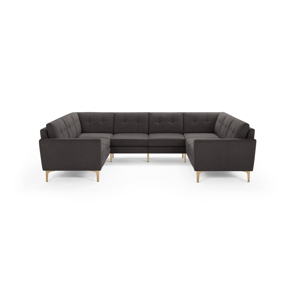 Dark gray fabric U-shaped sectional sofa with tufted cushions, straight arms, and light wooden legs on black background.