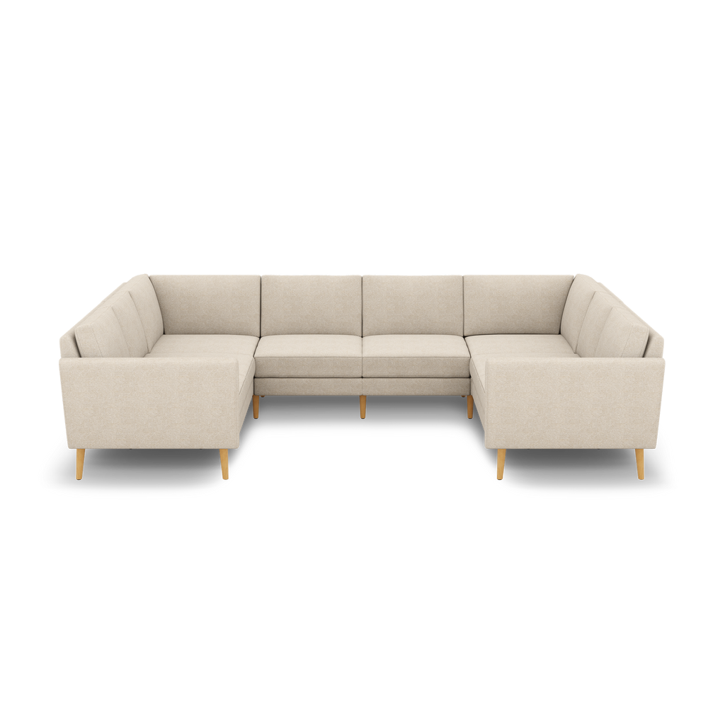 Beige fabric U-shaped sectional sofa with tufted cushions, low arms, and wooden tapered legs on black background.