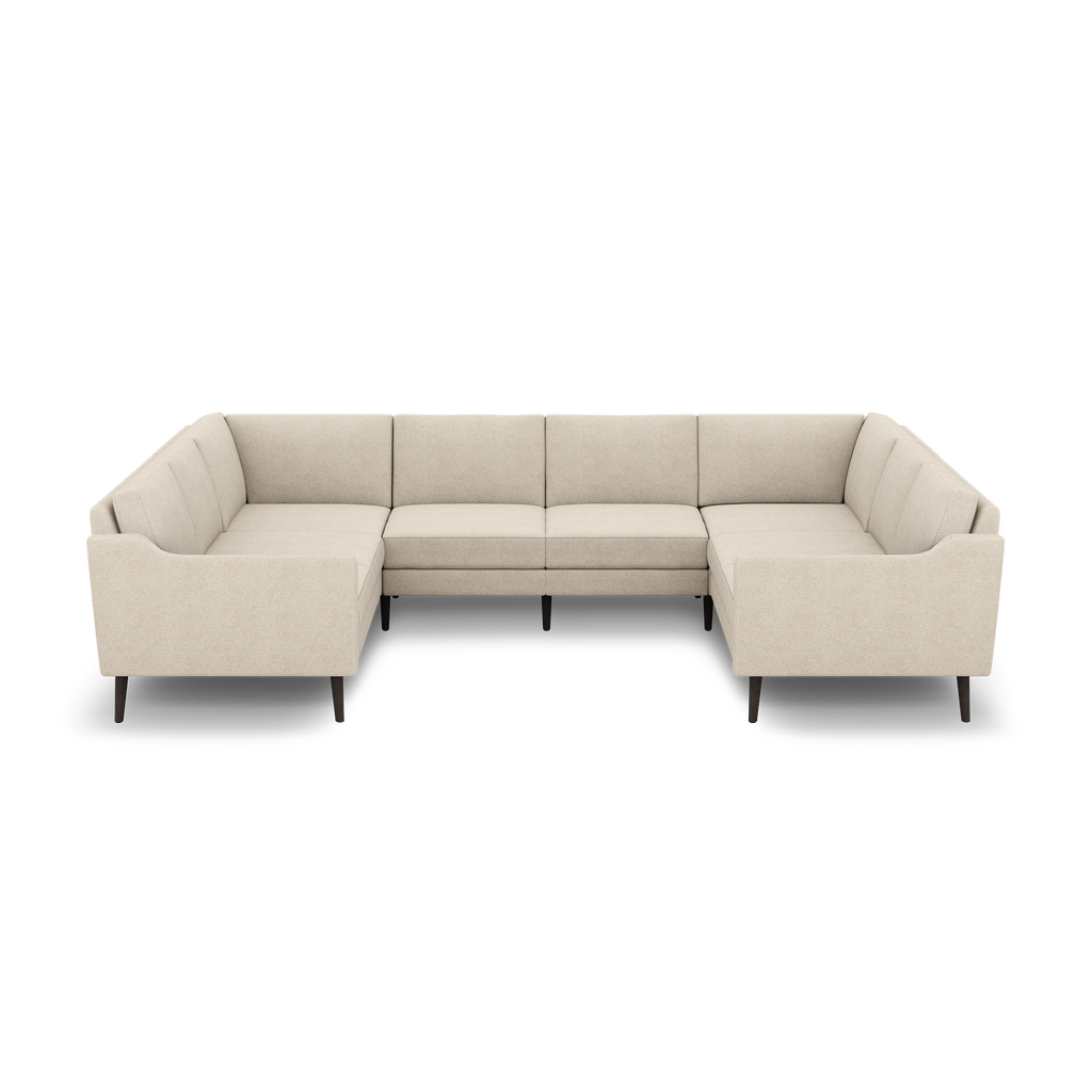 Beige L-shaped sectional sofa with tufted cushions, straight armrests, and dark tapered wooden legs, shown on black background.