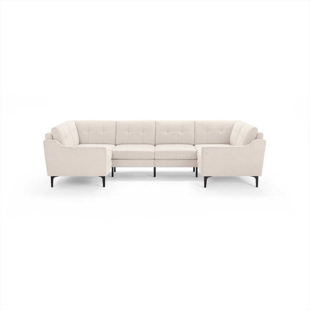 Cream-colored modern sectional sofa with tufted back cushions, angled armrests, and black metal legs on a clear background.