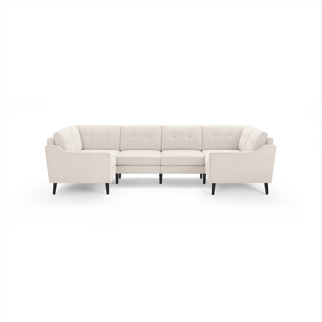 Light beige upholstered fabric sectional sofa with tufted back cushions and black tapered wooden legs, arranged in a U-shape.