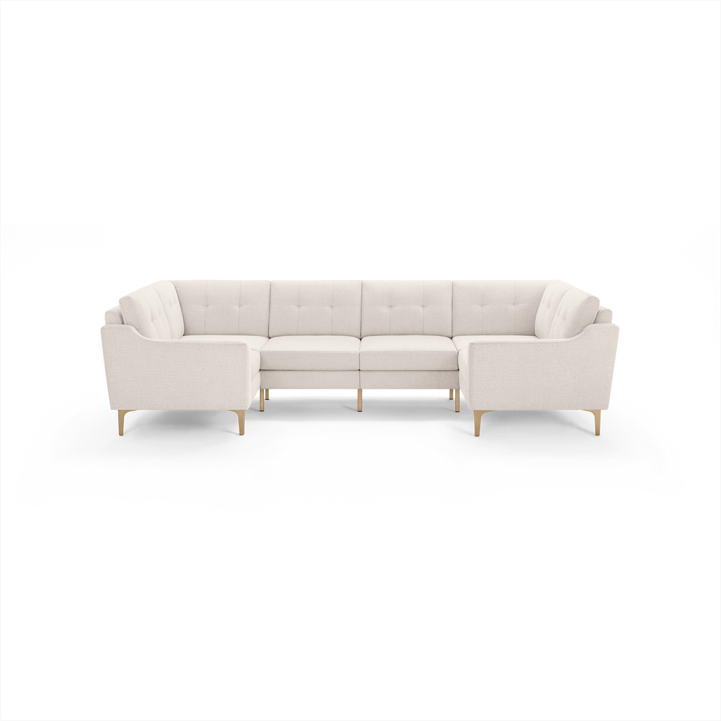 Cream-colored, L-shaped sectional sofa with tufted back cushions and wooden legs, featuring a modern, minimalist design.