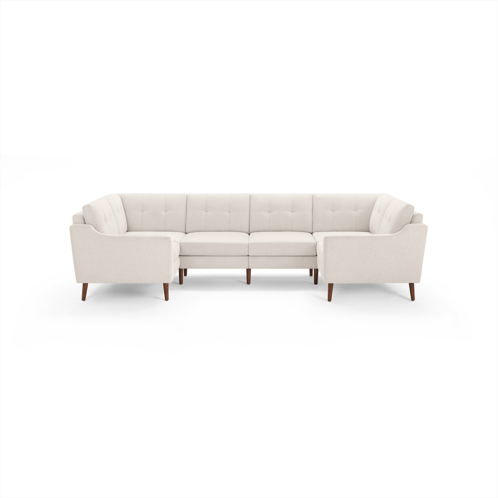 Cream-colored modern sectional sofa with tufted back cushions and wooden legs, designed for spacious seating.