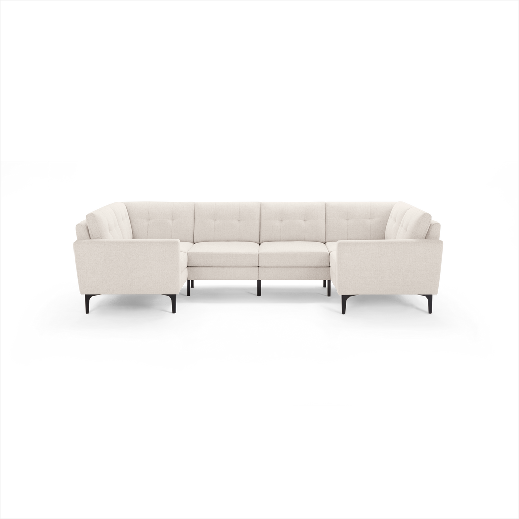Large modern U-shaped sectional sofa in light beige fabric with tufted back cushions and black metal legs.