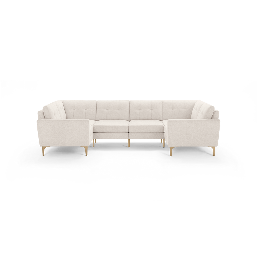 Light beige fabric U-shaped sectional sofa with tufted back cushions and wooden legs, designed for spacious seating.