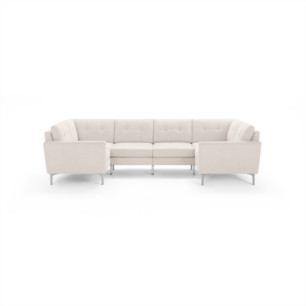 Beige tufted fabric sectional sofa with L-shape design, low armrests, and metal legs, shown on a black background.