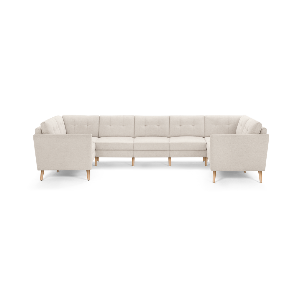 Cream-colored modern large U-shaped sectional sofa with tufted back cushions and light wooden legs.
