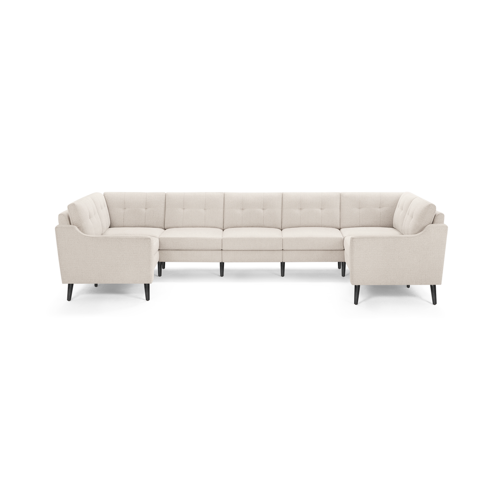 Beige fabric U-shaped sectional sofa with tufted back cushions and black tapered legs, designed for spacious seating.