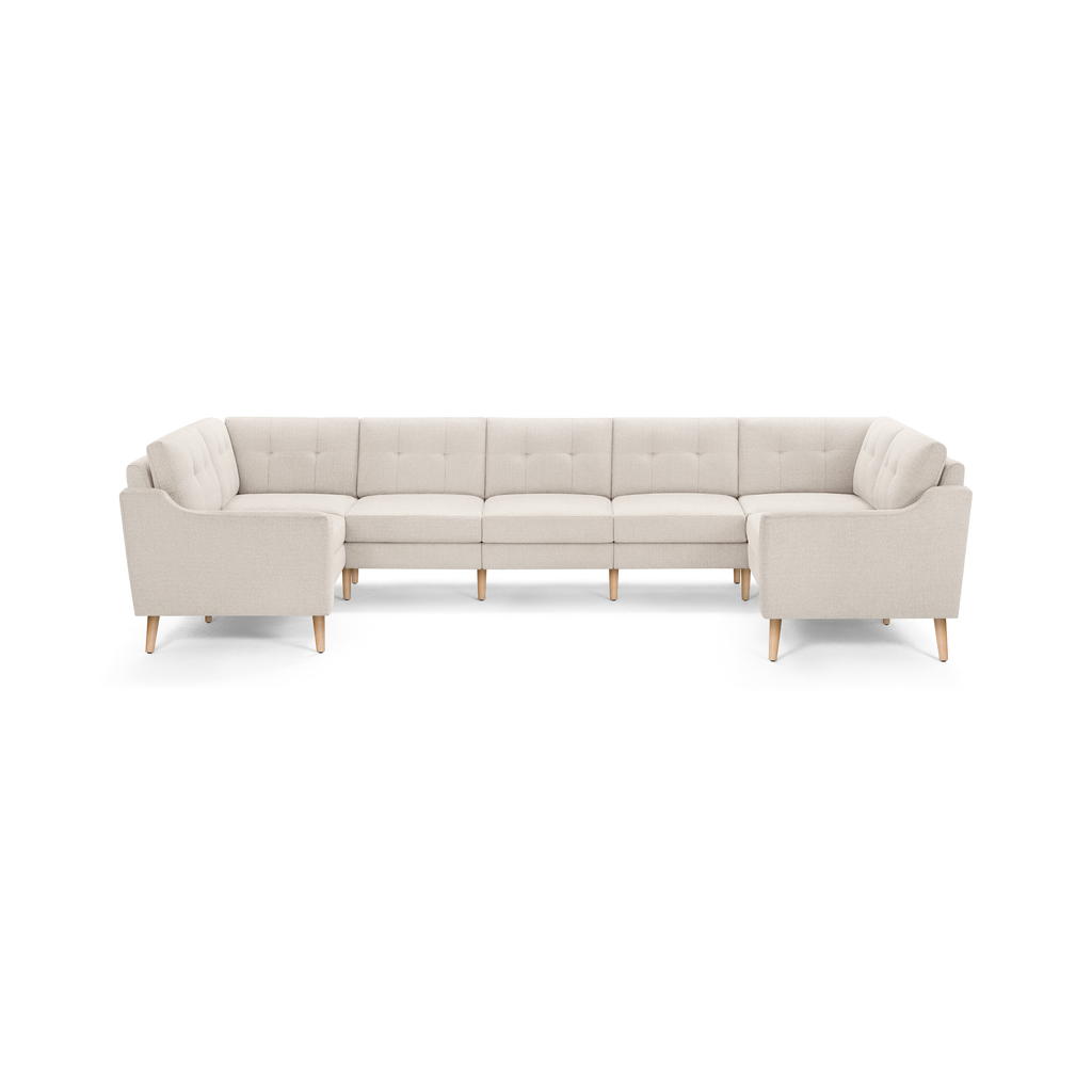 Large U-shaped sectional sofa with light beige fabric upholstery, tufted back cushions, and wooden tapered legs.