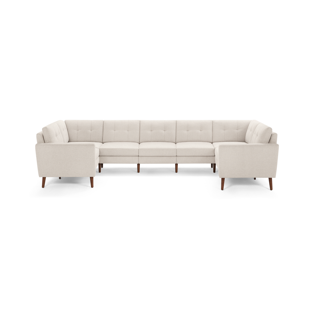 Large U-shaped sectional sofa in light beige fabric with button-tufted cushions and mid-century wooden legs.