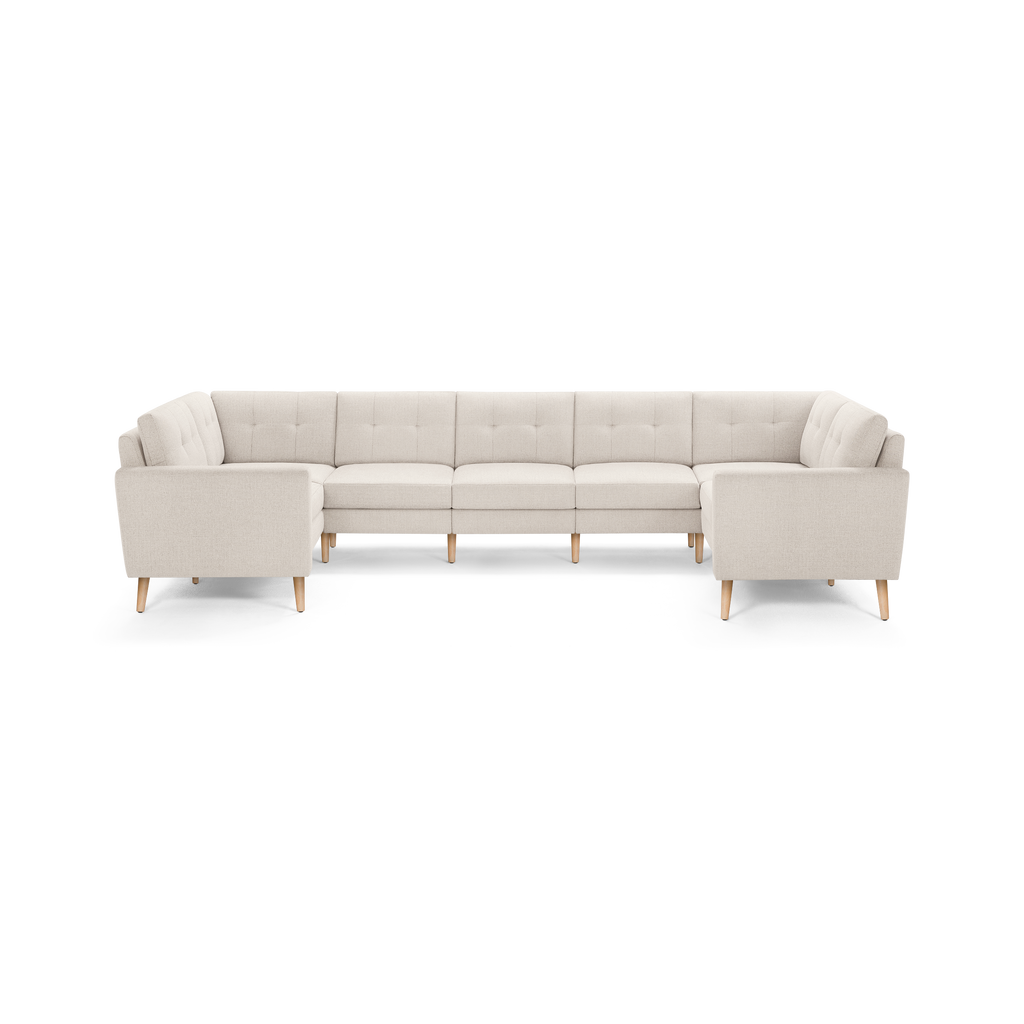 Beige L-shaped sectional sofa with tufted back cushions and light wooden legs, modern and minimalist design.