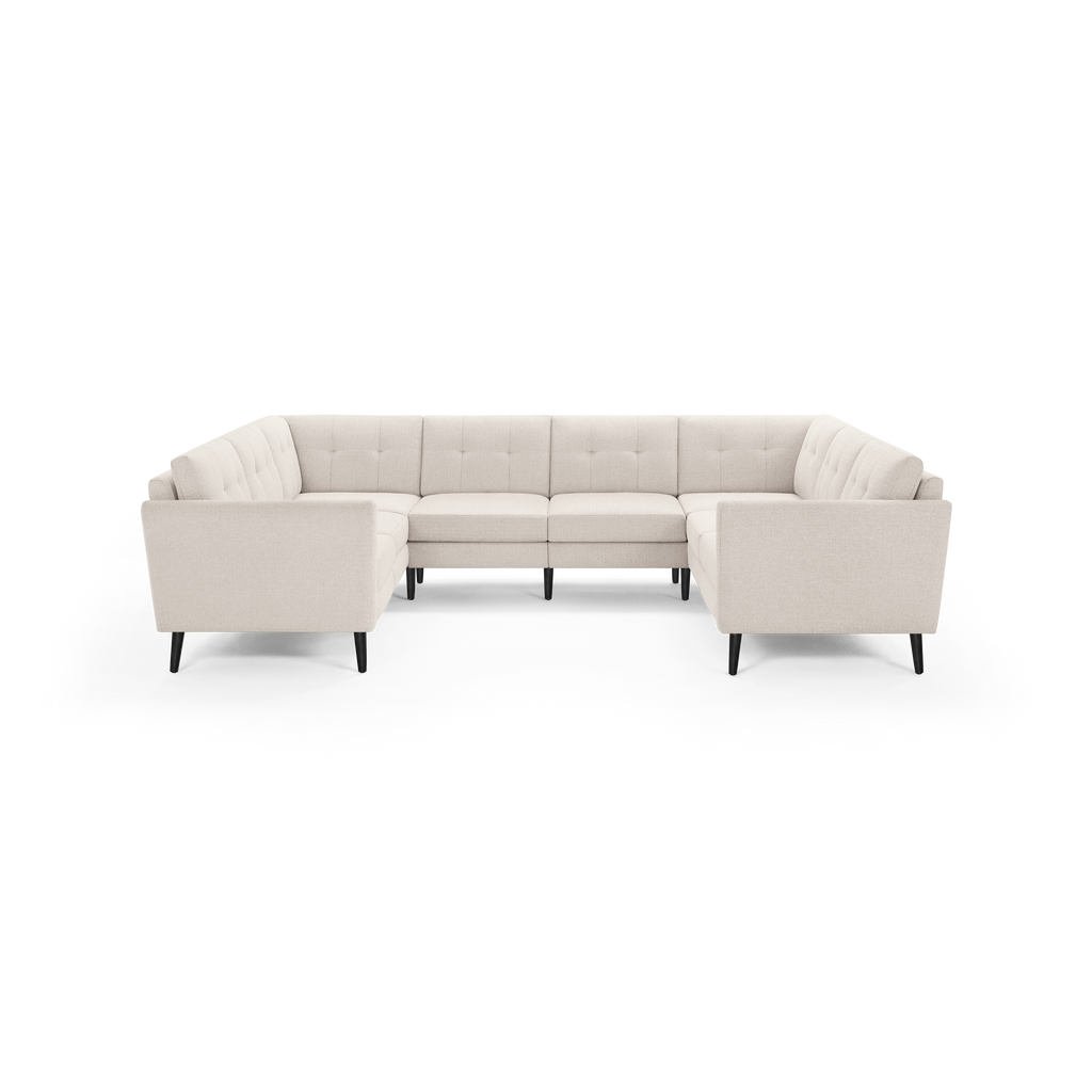 Light beige upholstered U-shaped sectional sofa with tufted back cushions and black tapered wooden legs.