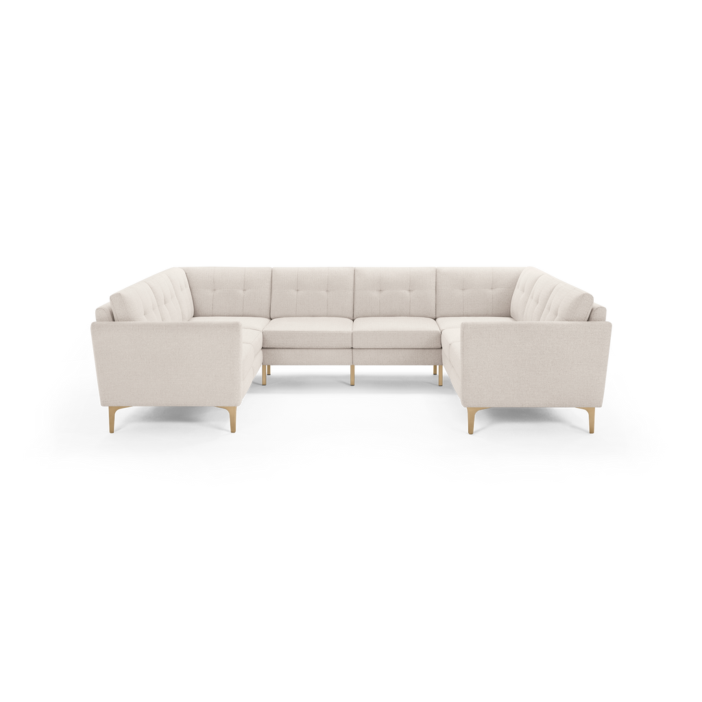Modern U-shaped sectional sofa upholstered in light beige fabric with tufted back cushions and light wooden legs.
