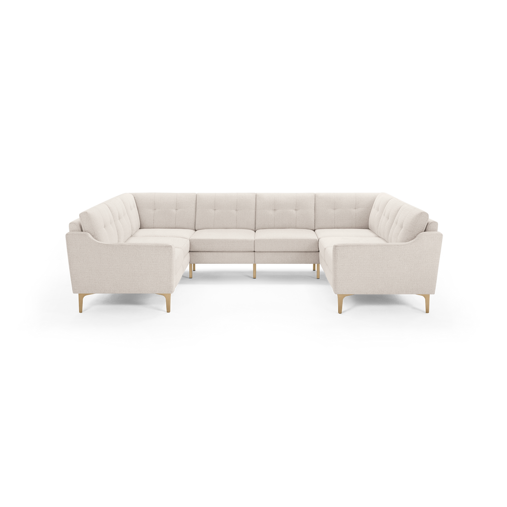 Light beige fabric upholstered U-shaped sectional sofa with tufted back cushions and wooden tapered legs.