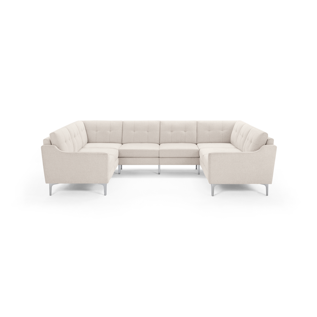 Beige sectional sofa with tufted back cushions, clean lines, silver metal legs, and a U-shaped design for spacious seating.