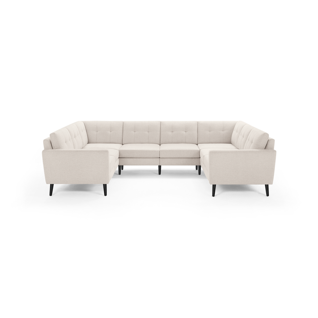 Modern U-shaped sectional sofa in light beige fabric with tufted cushions and black tapered legs, spacious for seating multiple people.