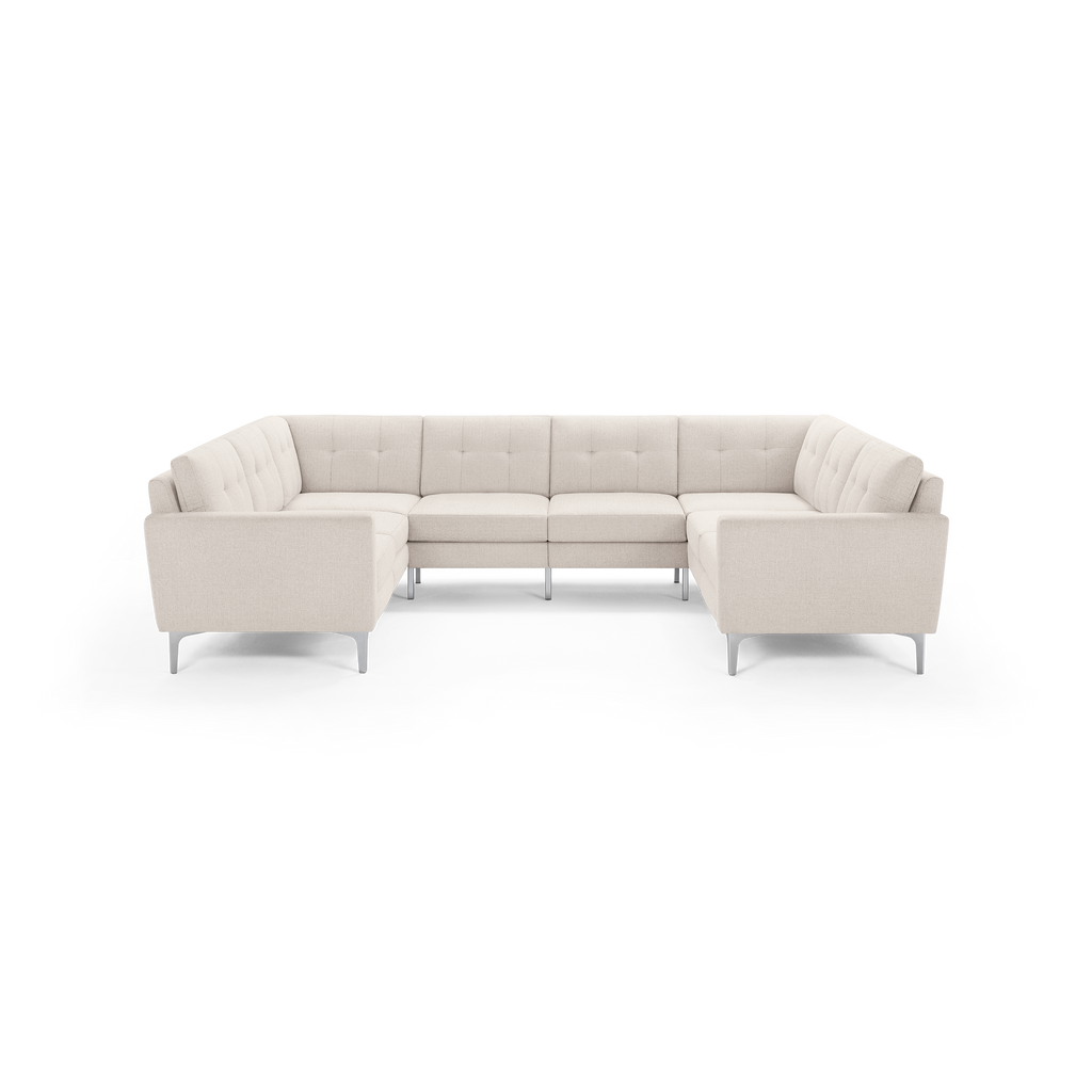 U-shaped sectional sofa in light beige fabric with tufted cushions and slim silver metal legs.