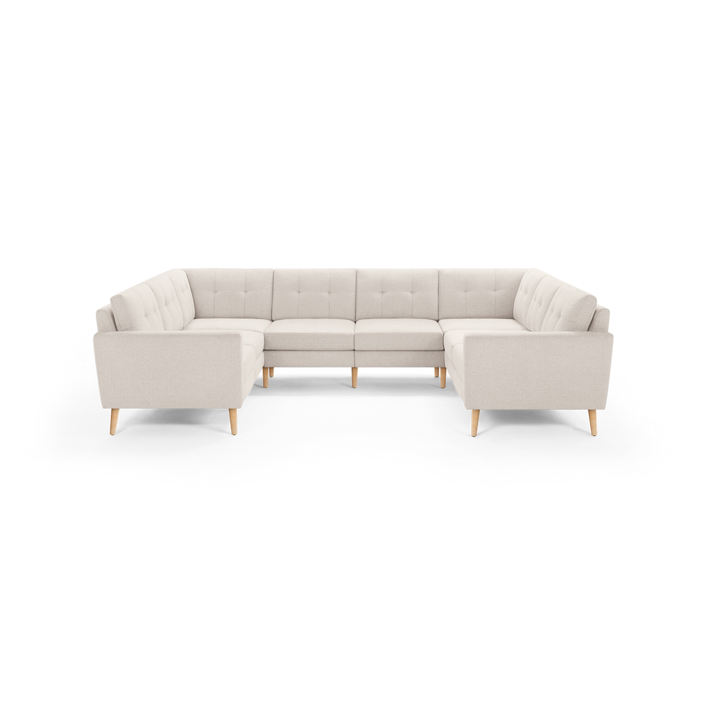 Light beige large U-shaped sectional sofa with tufted cushions and wooden legs, designed for spacious living rooms.
