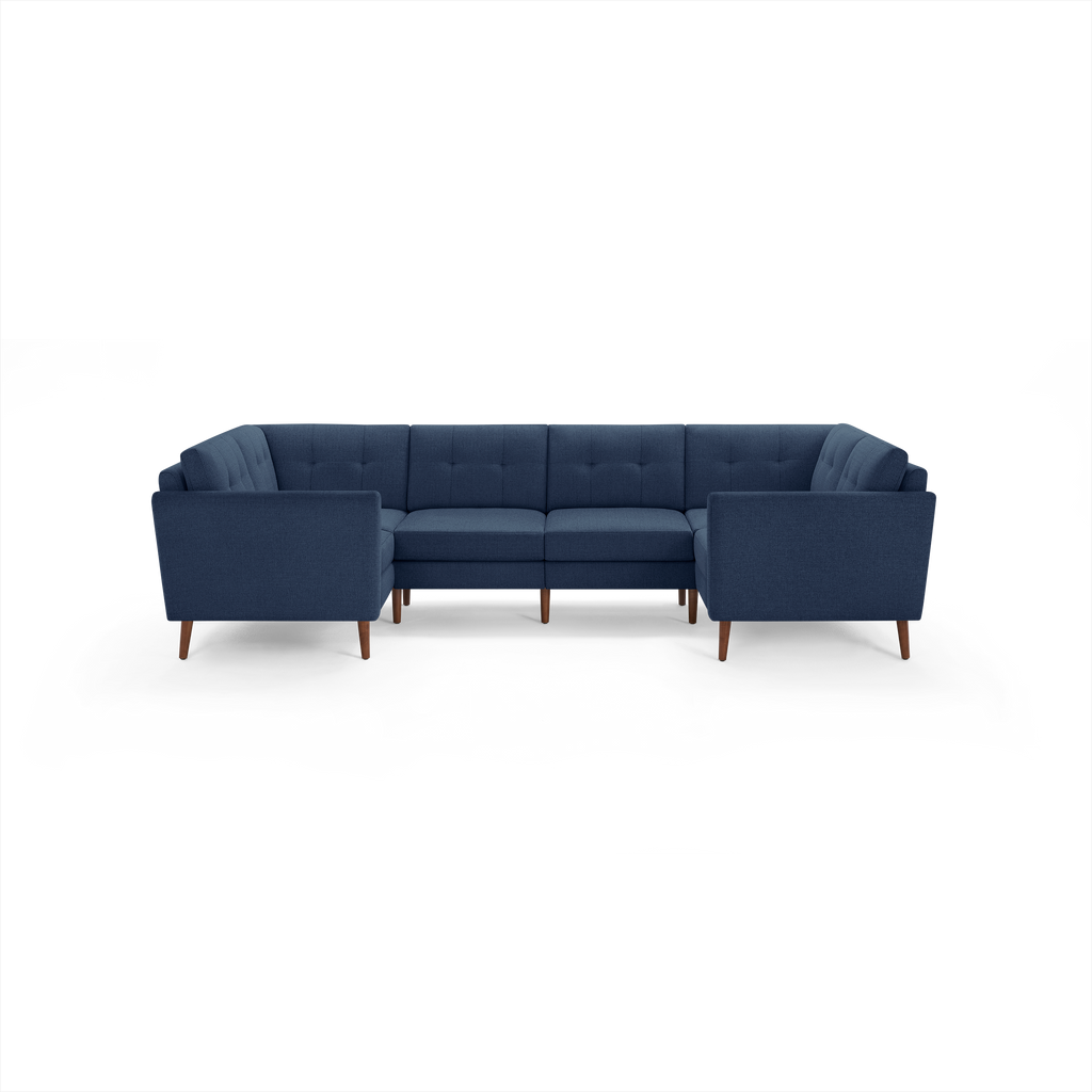 Dark blue fabric U-shaped sectional sofa with tufted back cushions and wooden legs, designed for spacious living areas.