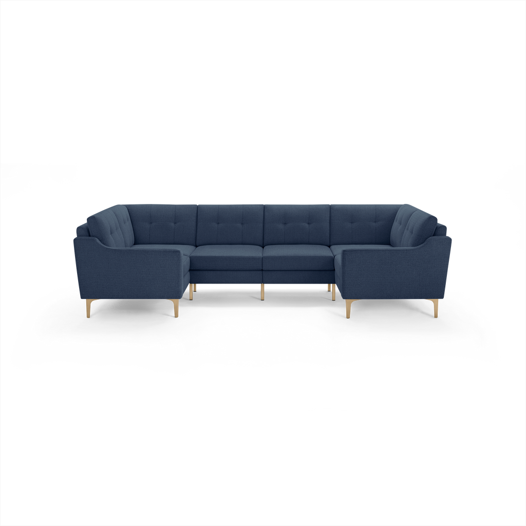 Modern deep blue fabric sectional sofa with tufted back cushions and light wood legs, designed for spacious corner seating.