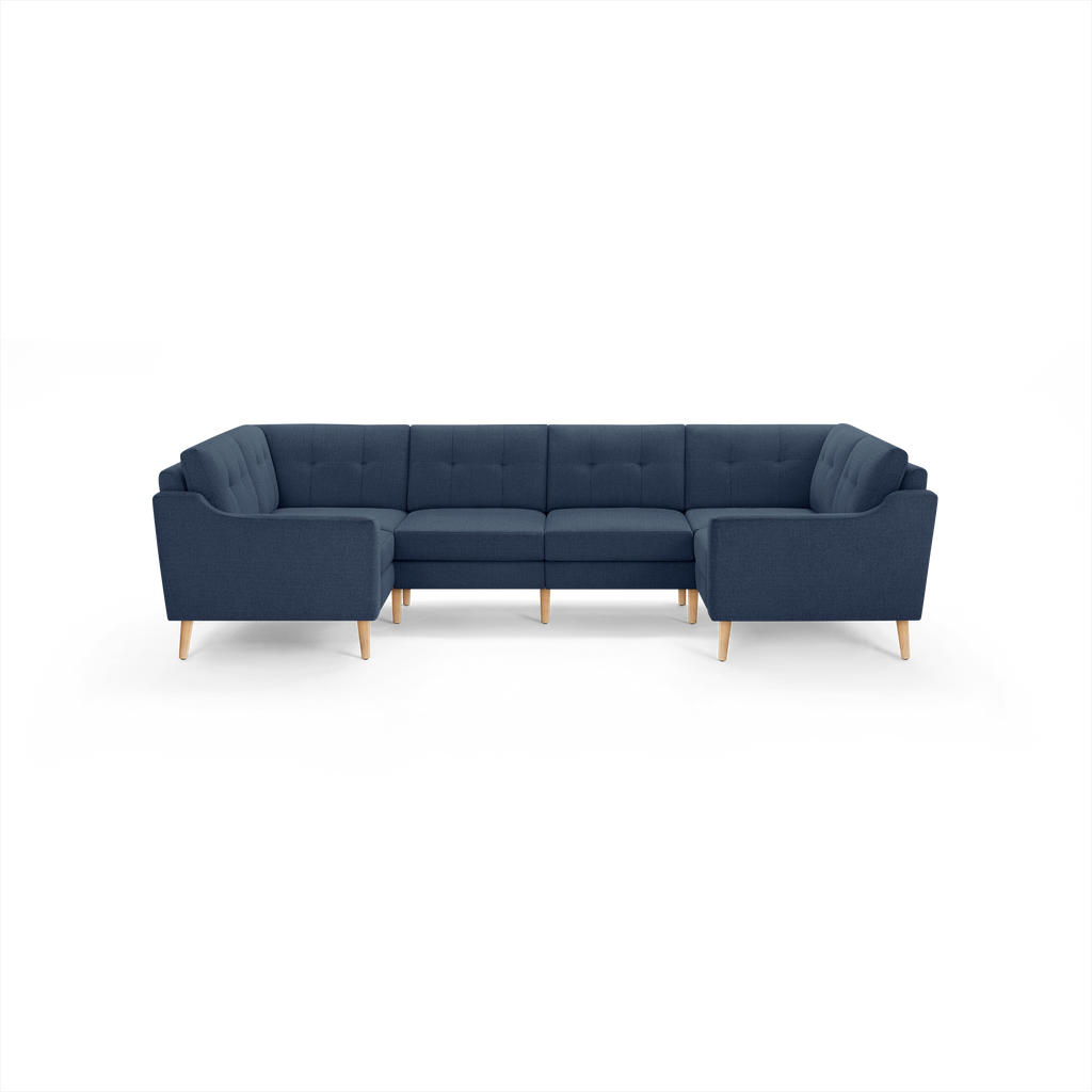 Large U-shaped sectional sofa upholstered in dark blue fabric with tufted back cushions and light wooden legs.