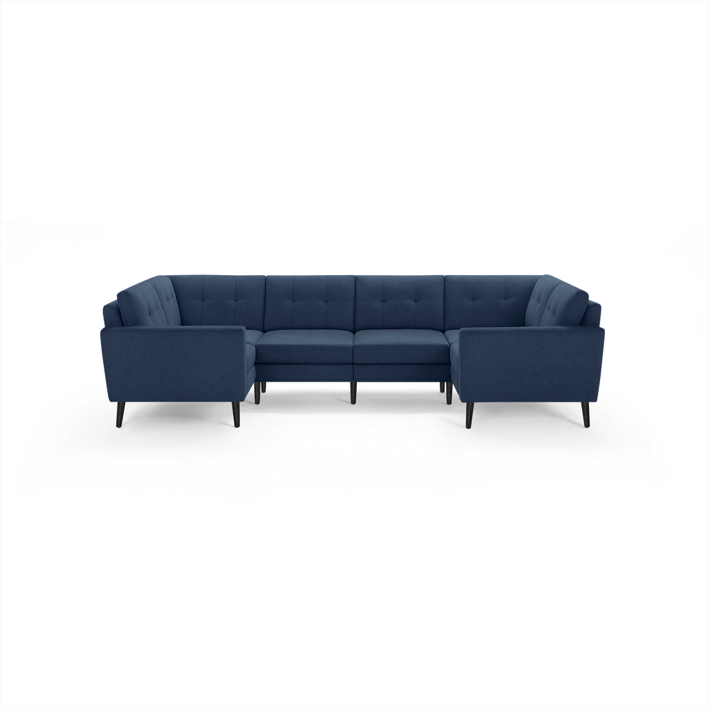 Modern navy blue fabric sectional sofa with tufted back cushions, straight armrests, and slim black legs on a black background.
