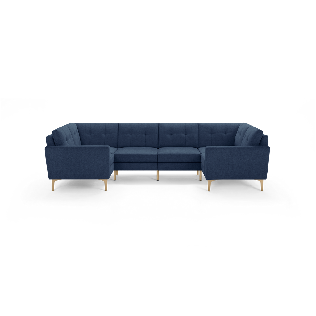 Large navy blue L-shaped sectional sofa with tufted back cushions and light wooden legs, modern and minimalist design.