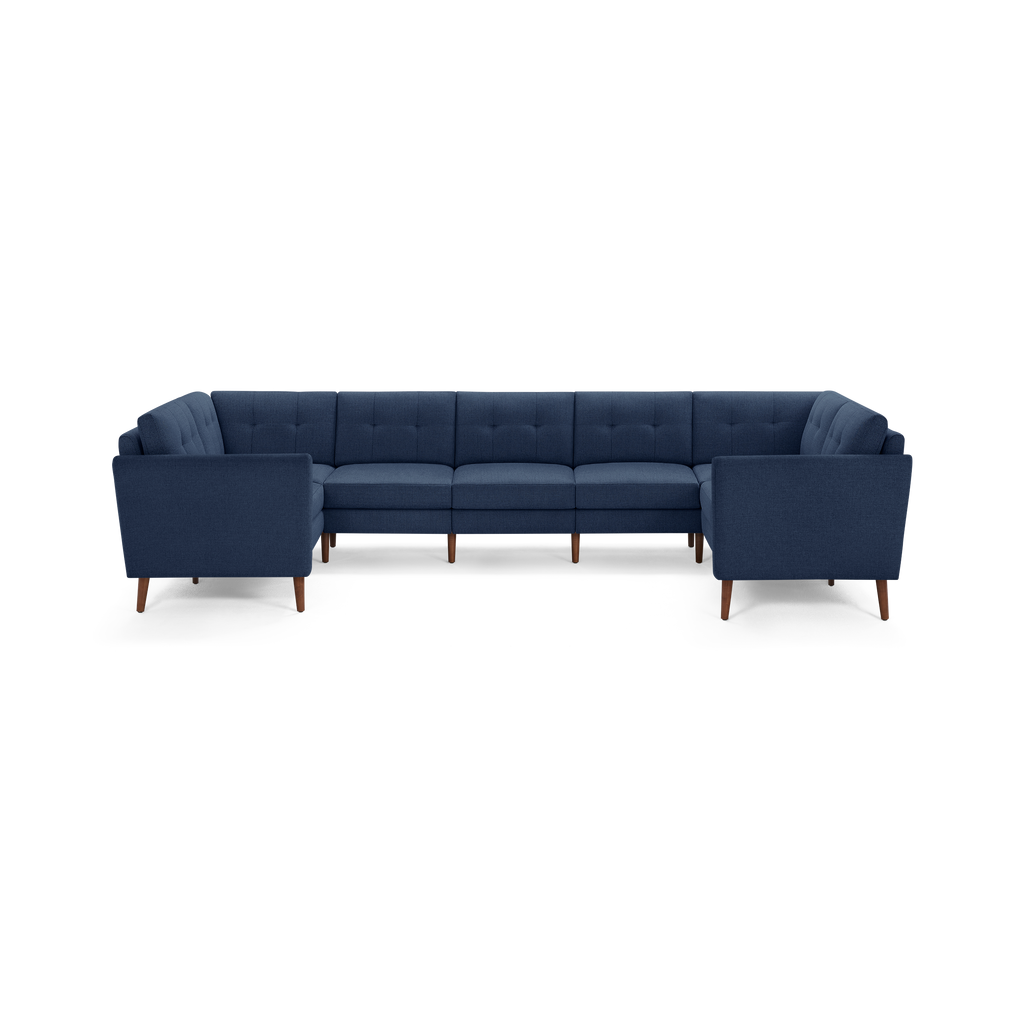 Large modern U-shaped sectional sofa with deep blue fabric upholstery and wooden legs, featuring tufted back cushions.