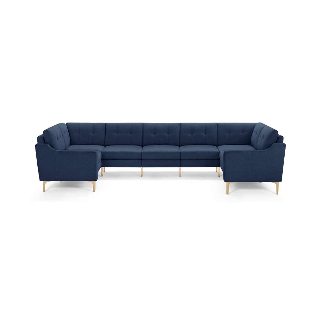 Large modern U-shaped sectional sofa in dark blue fabric with tufted cushions and light wooden legs.