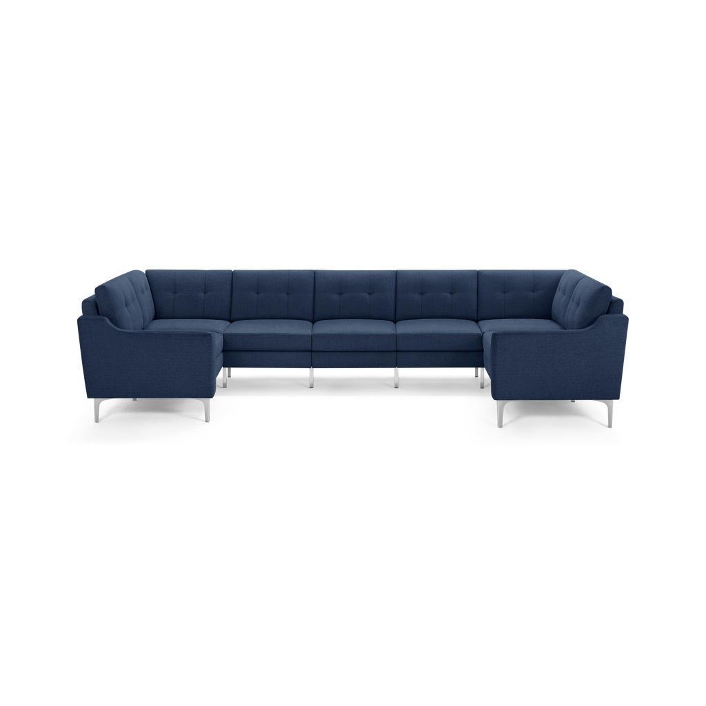 Large modern U-shaped sectional sofa in dark blue fabric with tufted cushions and slim metal legs, offering ample seating space.