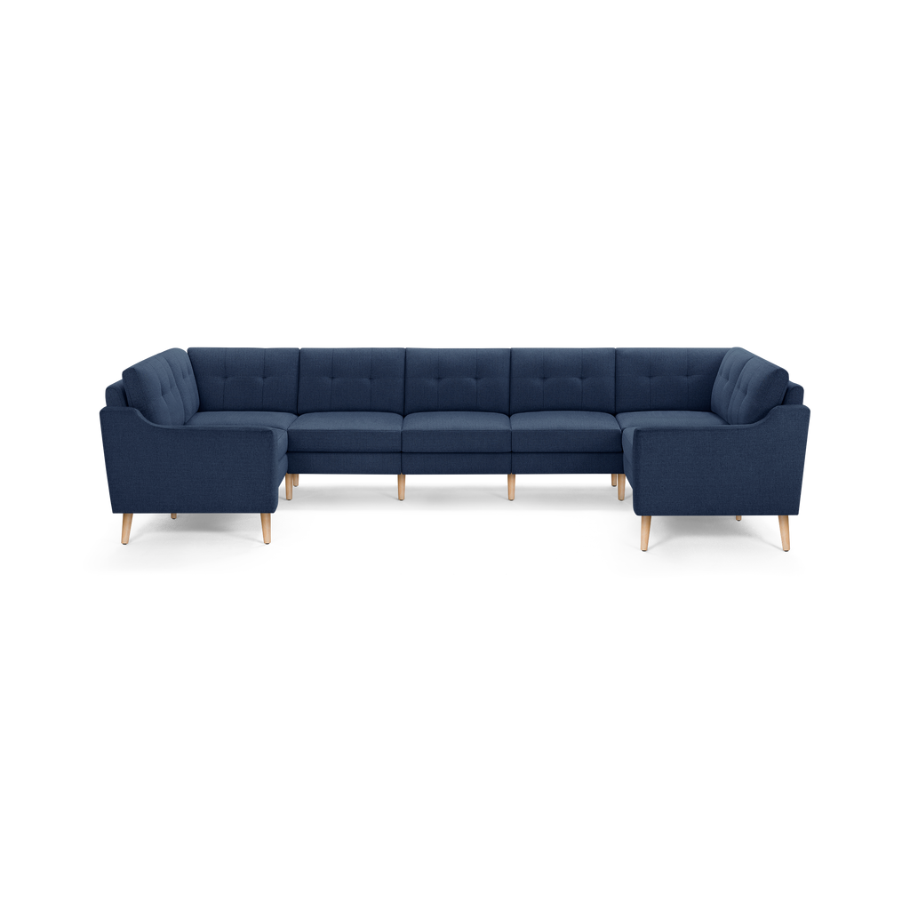 Large U-shaped sectional sofa in dark blue fabric with tufted back cushions and light wooden legs, designed for spacious seating.