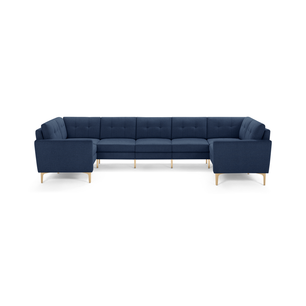 Large navy blue sectional sofa with tufted back cushions, clean lines, and light wooden legs.