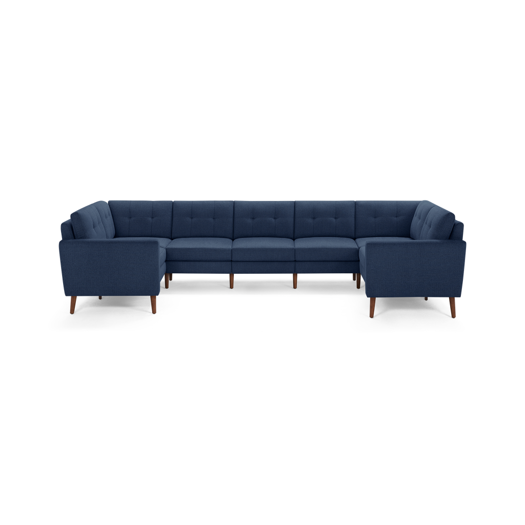 Large navy blue fabric sectional sofa with tufted back cushions and angled wooden legs on a white background.