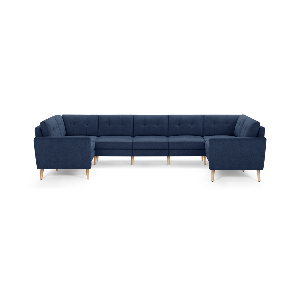 Large U-shaped sectional sofa in navy blue fabric with tufted cushions and light wooden legs, modern design.