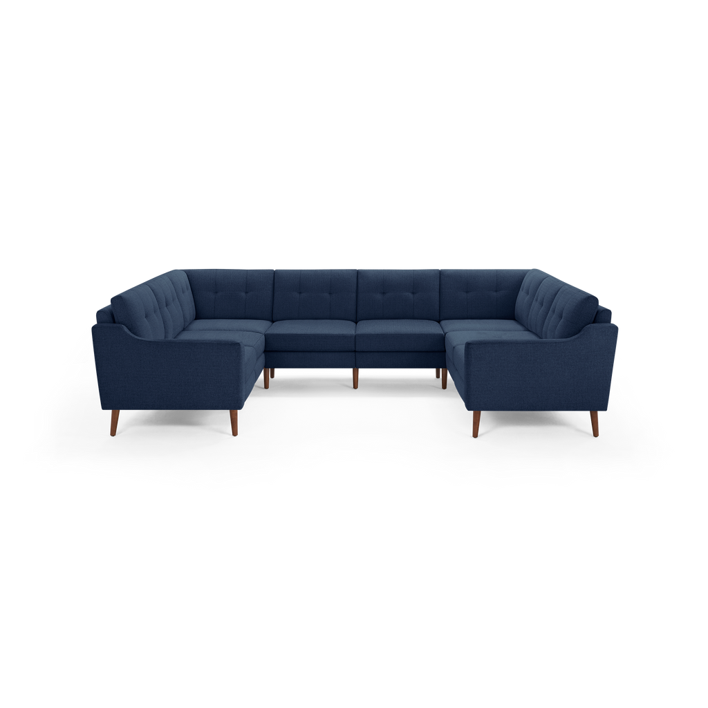 Large navy blue fabric sectional sofa with tufted back cushions and wooden tapered legs, designed in a U-shape for ample seating.