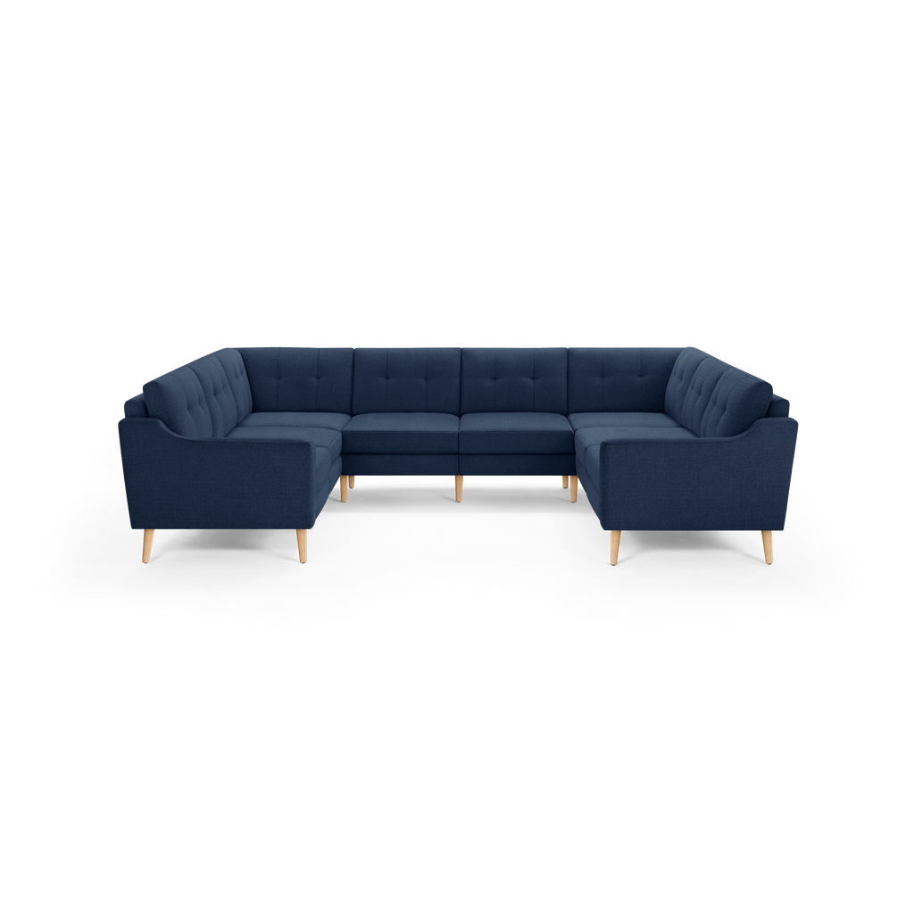 Large navy blue U-shaped sectional sofa with tufted cushions and light wooden legs, designed for spacious living rooms.