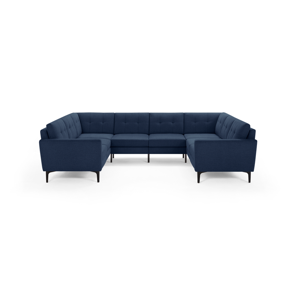 Large modern U-shaped sectional sofa upholstered in dark blue fabric with tufted cushions and slim black legs.